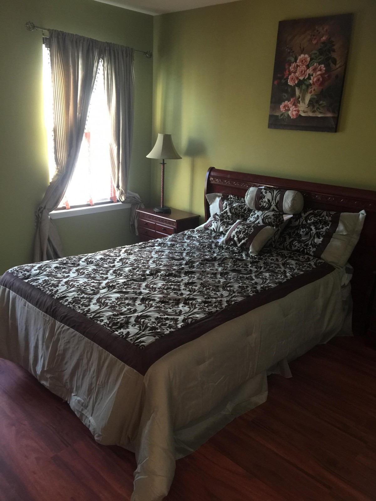 A cozy bedroom with a neatly made bed and decorative pillows beside a window with curtains.