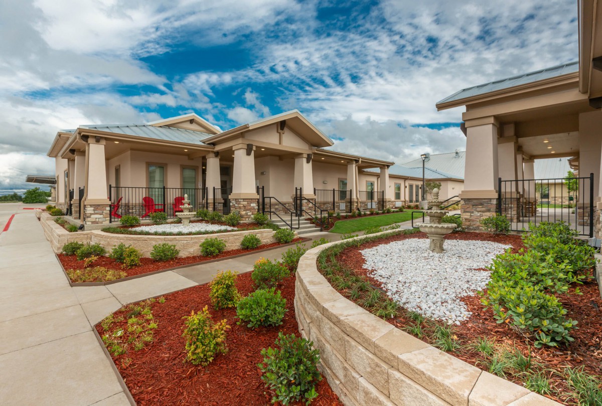 A scenic view of houses with beautifully landscaped gardens and pathways under a cloudy sky.