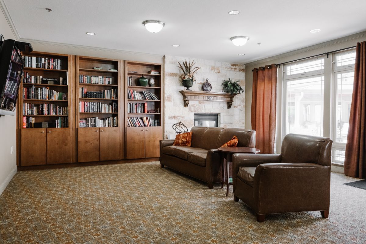 A cozy living room with bookshelves, a sofa, and a fireplace.