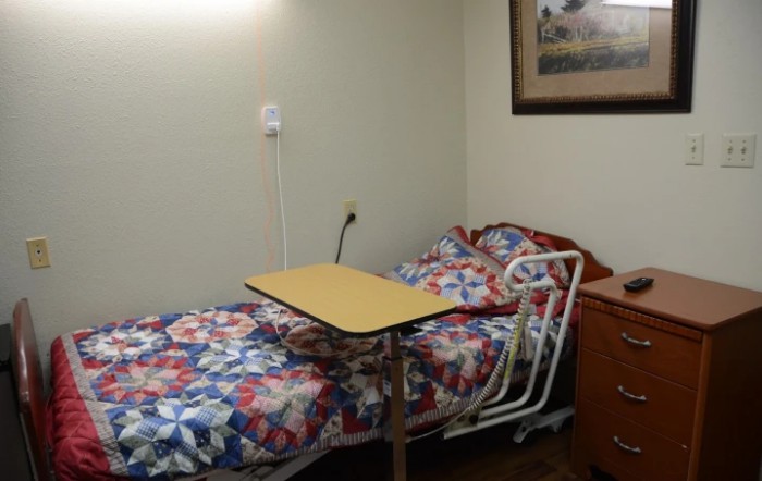 A hospital room with a single bed and overbed table.