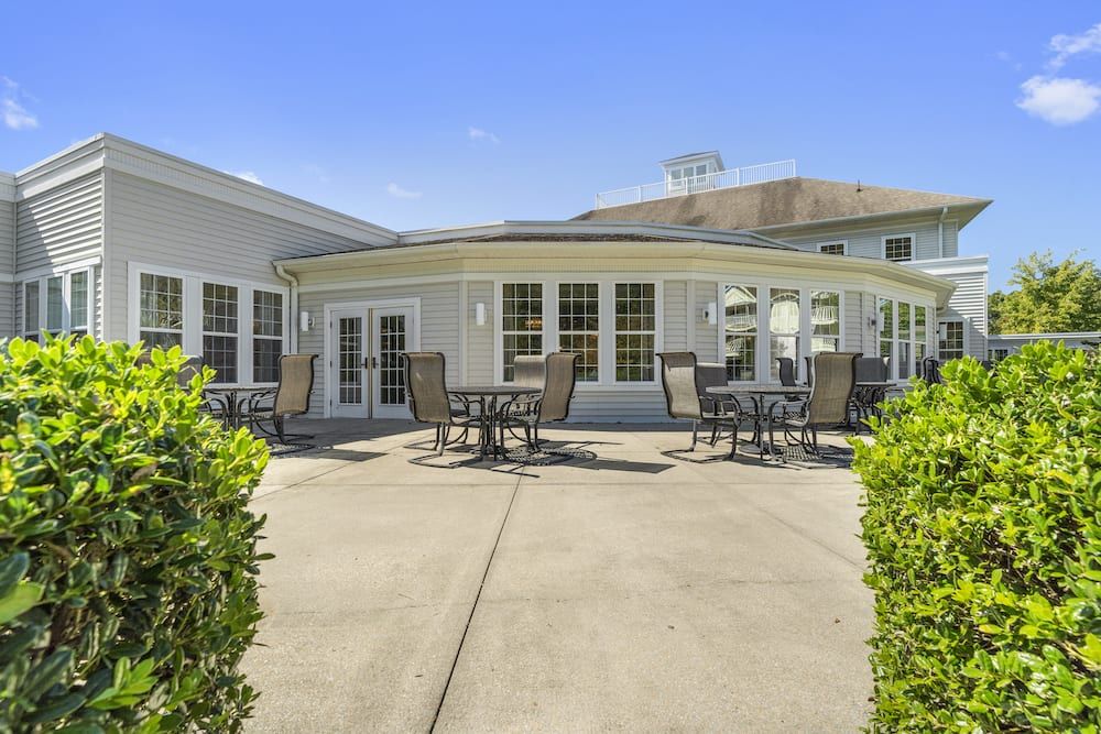 A sunny outdoor patio area with chairs and tables in front of a building.