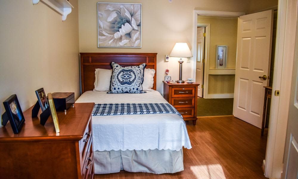 A cozy bedroom with a neatly made bed, wooden furniture, and soft lighting.
