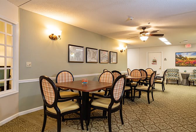 A cozy dining room with several tables and chairs, adorned with wall art and warm lighting.