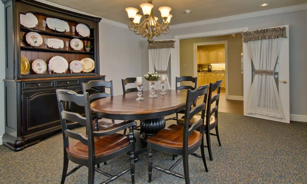 A cozy dining room featuring a round wooden table with matching chairs and an elegant chandelier overhead.