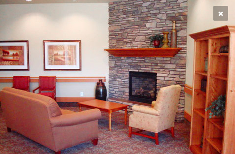 A cozy living room with a stone fireplace and comfortable seating.