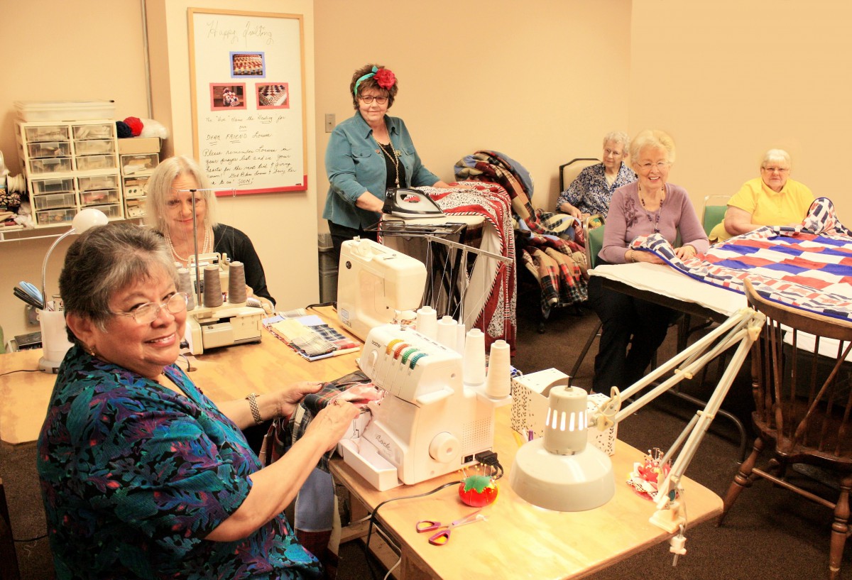 A group of women engaged in sewing and crafting activities in an indoor setting.