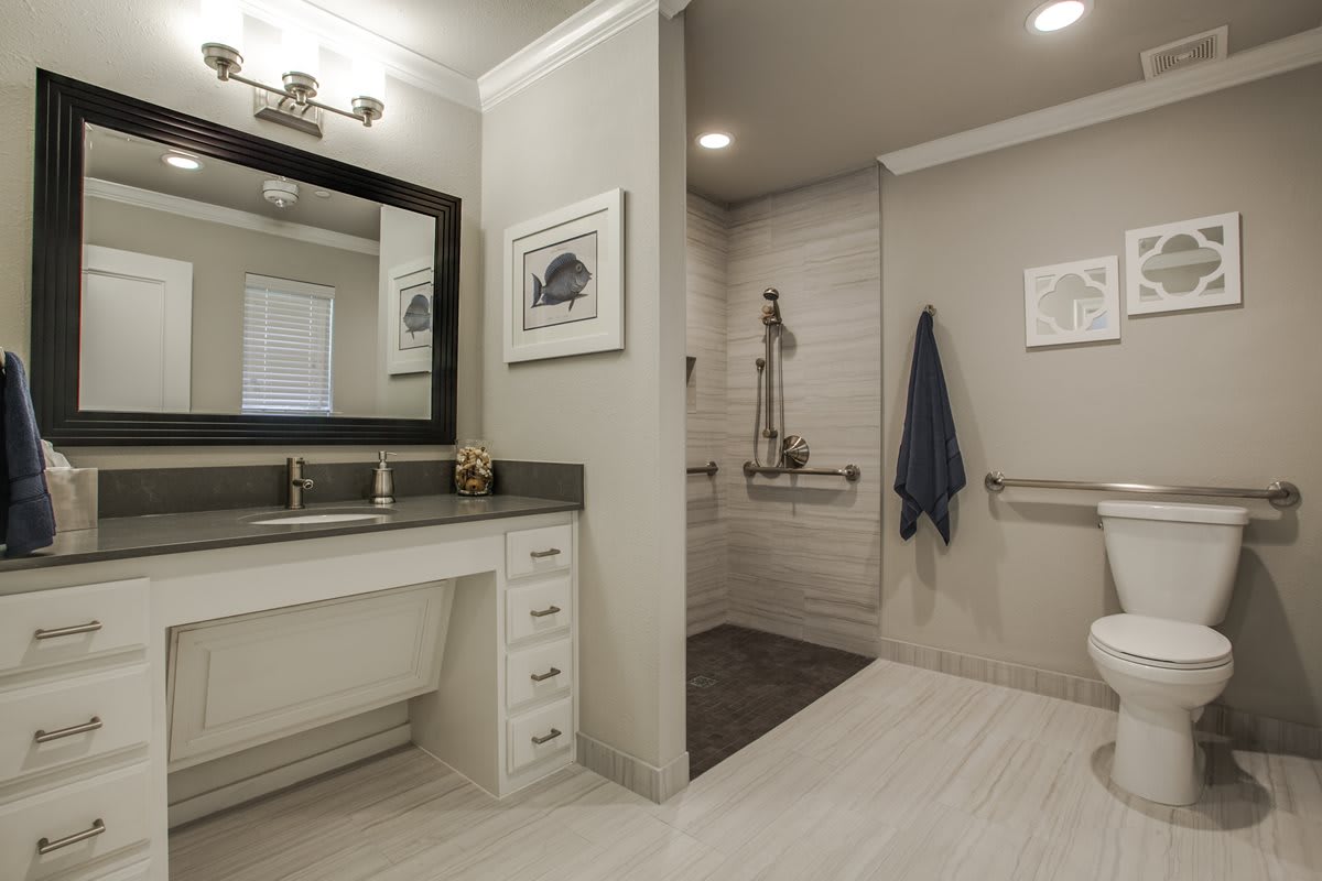 A modern bathroom with a large mirror, sleek vanity, and a walk-in shower.
