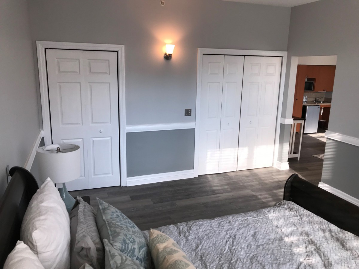 A modern bedroom with grey walls, white doors, and stylish lighting.