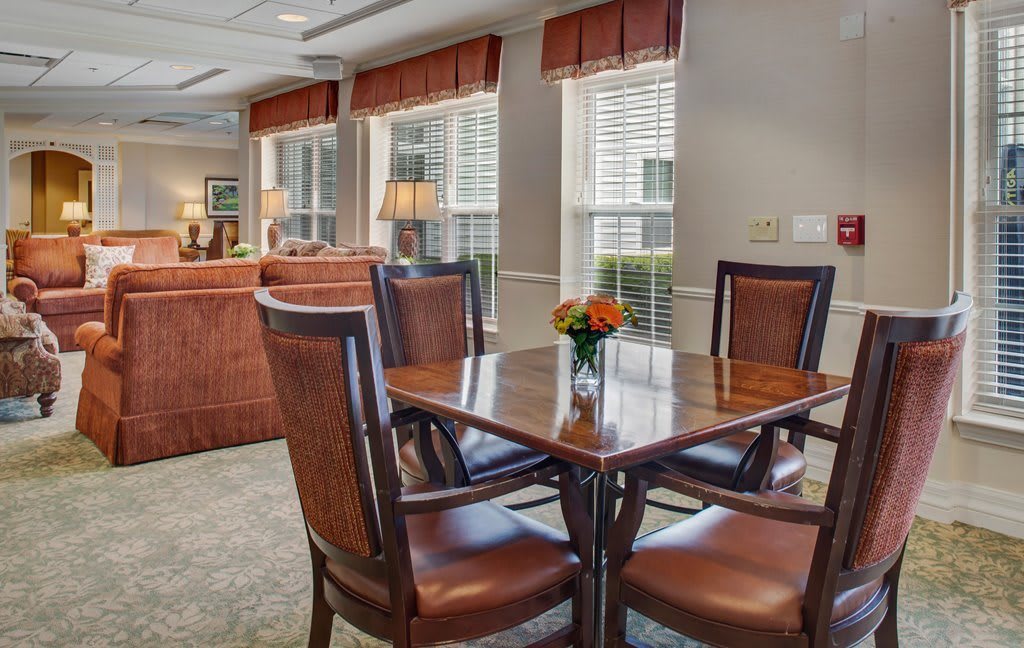 A cozy dining area with a wooden table, surrounded by chairs and decorated with a flower centerpiece.