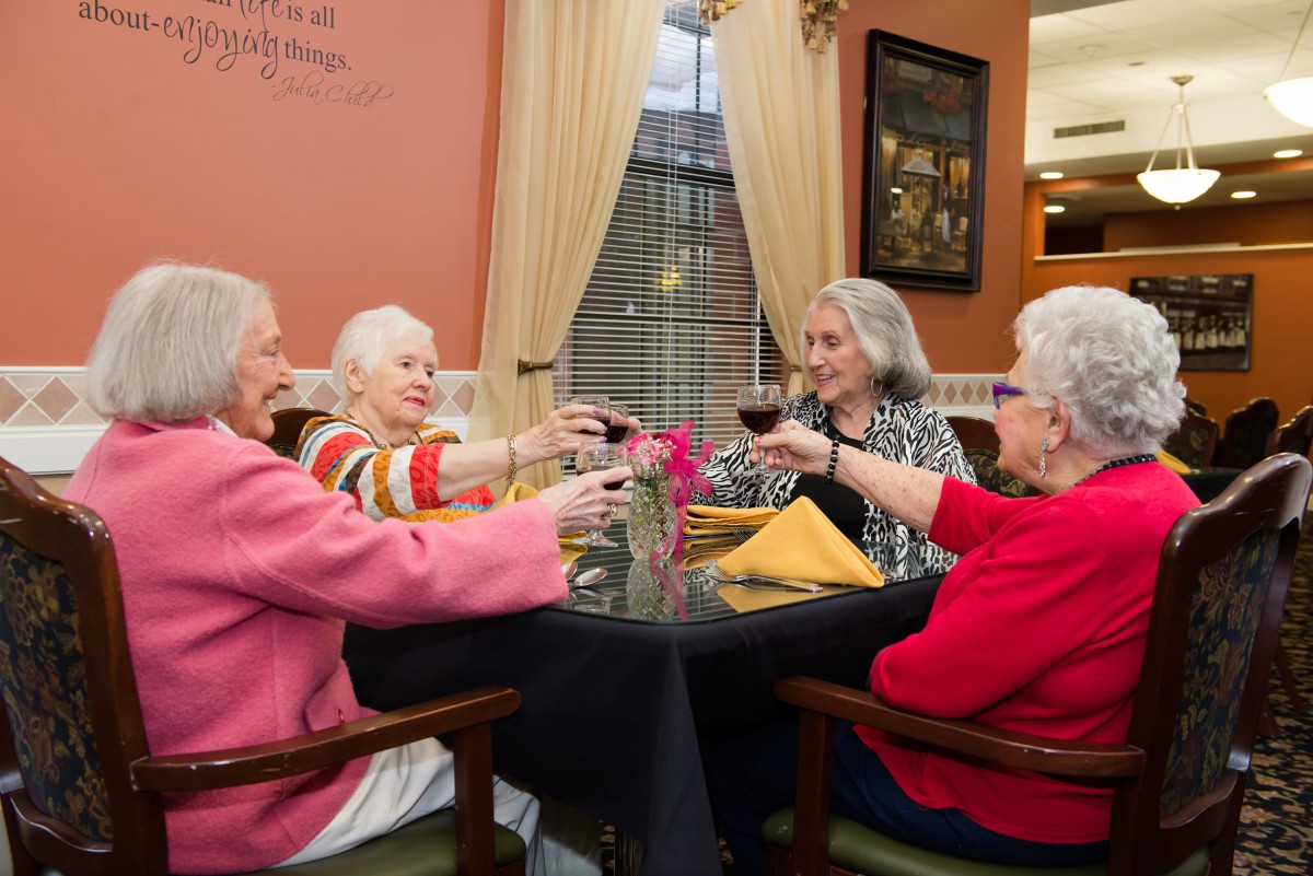 A group of senior women enjoying a toast together at a dining table.