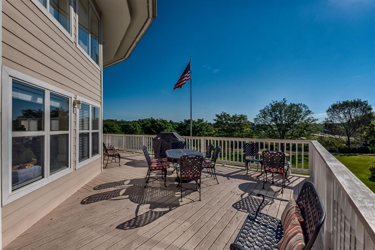 A scenic outdoor deck with patio furniture and an American flag under a clear blue sky.