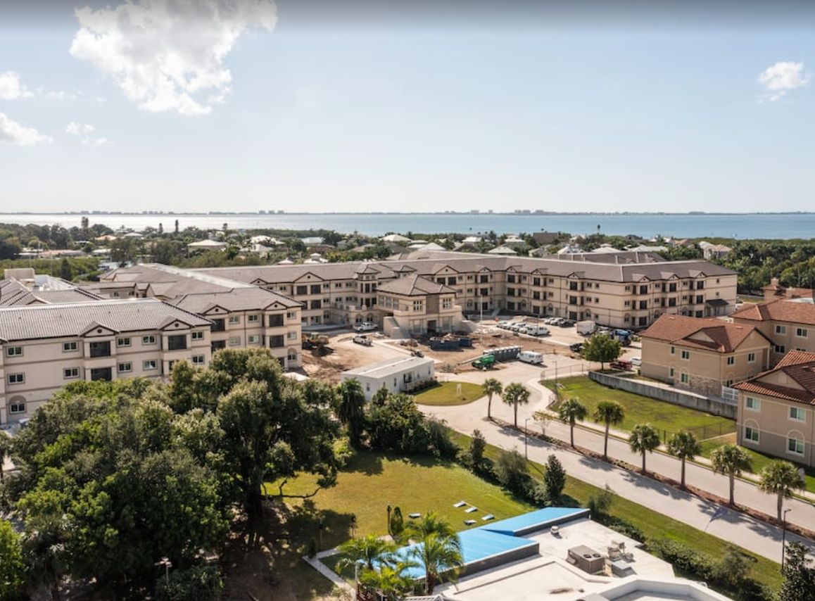A scenic aerial view of a resort complex with palm trees and coastline in the background.