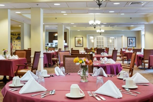 A sophisticated dining area with neatly arranged tables and chairs, featuring elegant place settings and floral centerpieces.