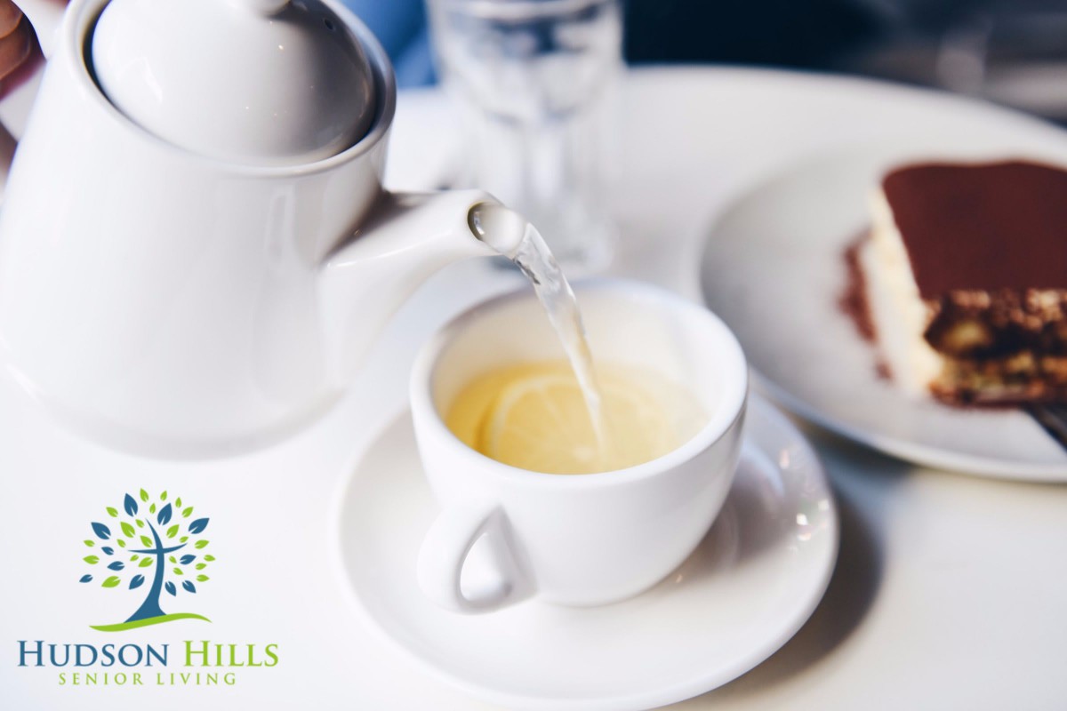 A teapot pouring tea into a cup on a table.