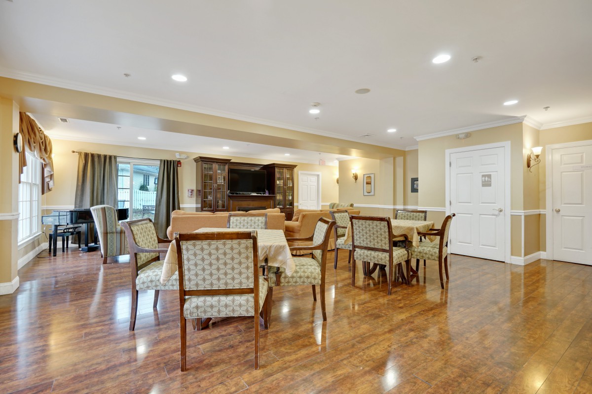 A spacious indoor dining area with tables and chairs on a wooden floor.
