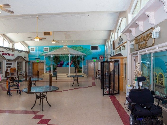 An empty indoor space featuring tables, chairs, a gazebo, and a mural on the wall.