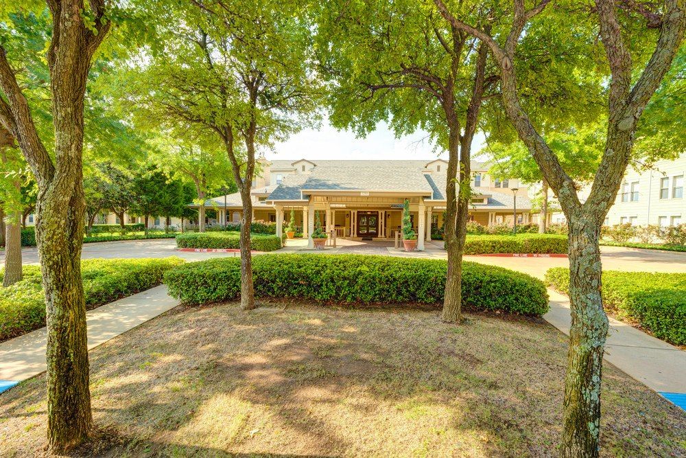 A view of a building surrounded by trees and greenery with a pathway leading to the entrance.