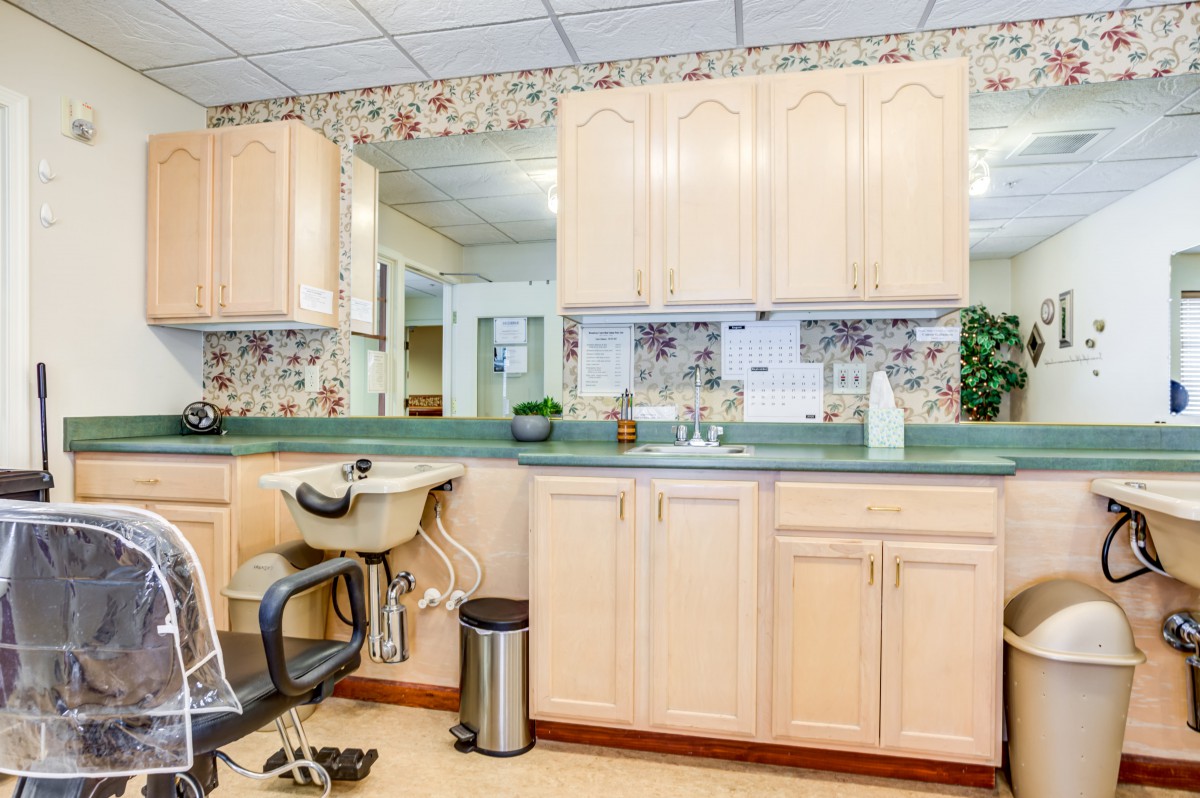 A spacious salon area featuring a hair washing station with cabinets and mirrors.