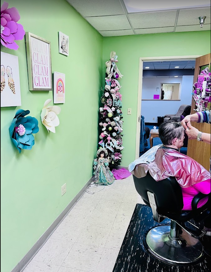 A beauty salon with a hairdresser styling a client's hair, featuring festive decorations and a Christmas tree.
