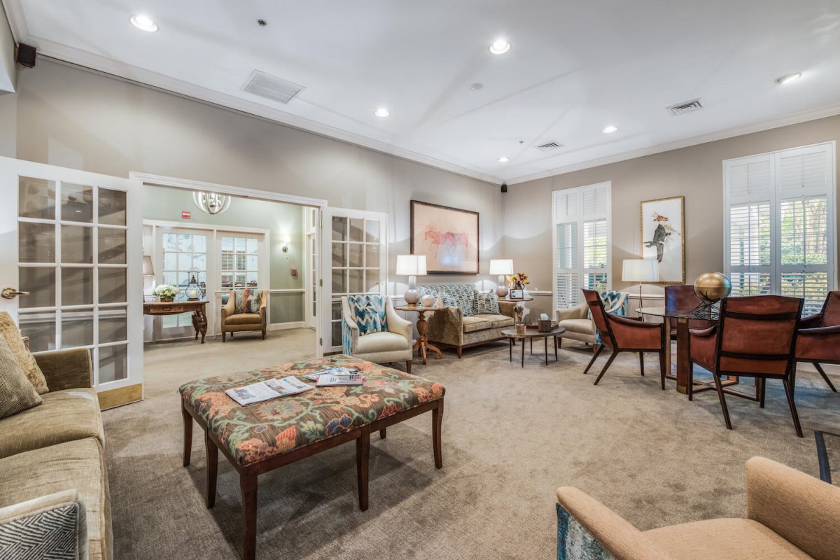 A spacious and well-furnished living room with sofas, tables, and artwork on the walls.