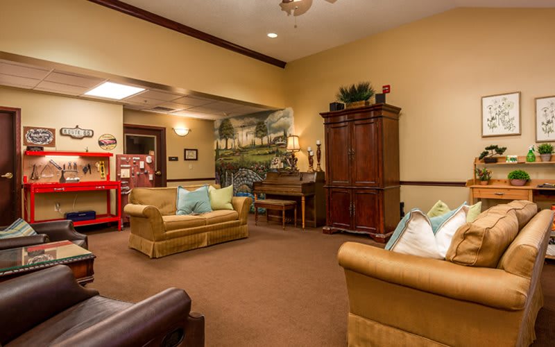 A cozy living room with comfortable sofas, a wooden cabinet, and warm lighting.