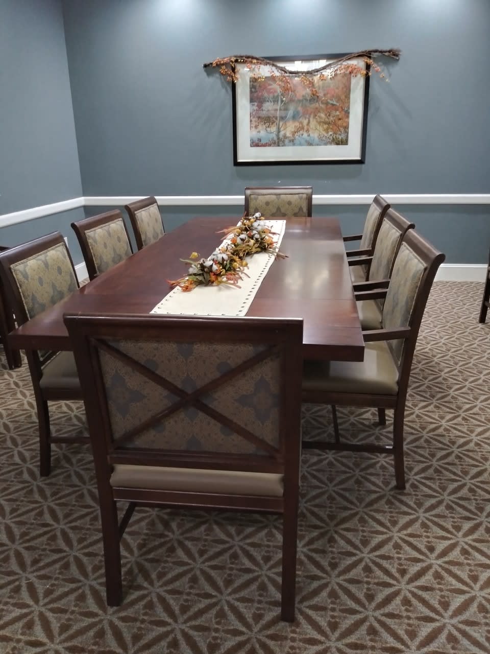 A neatly arranged dining room with a wooden table, chairs, and decorative centerpiece.