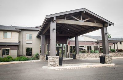 A modern hotel entrance with stone pillars and a covered driveway.