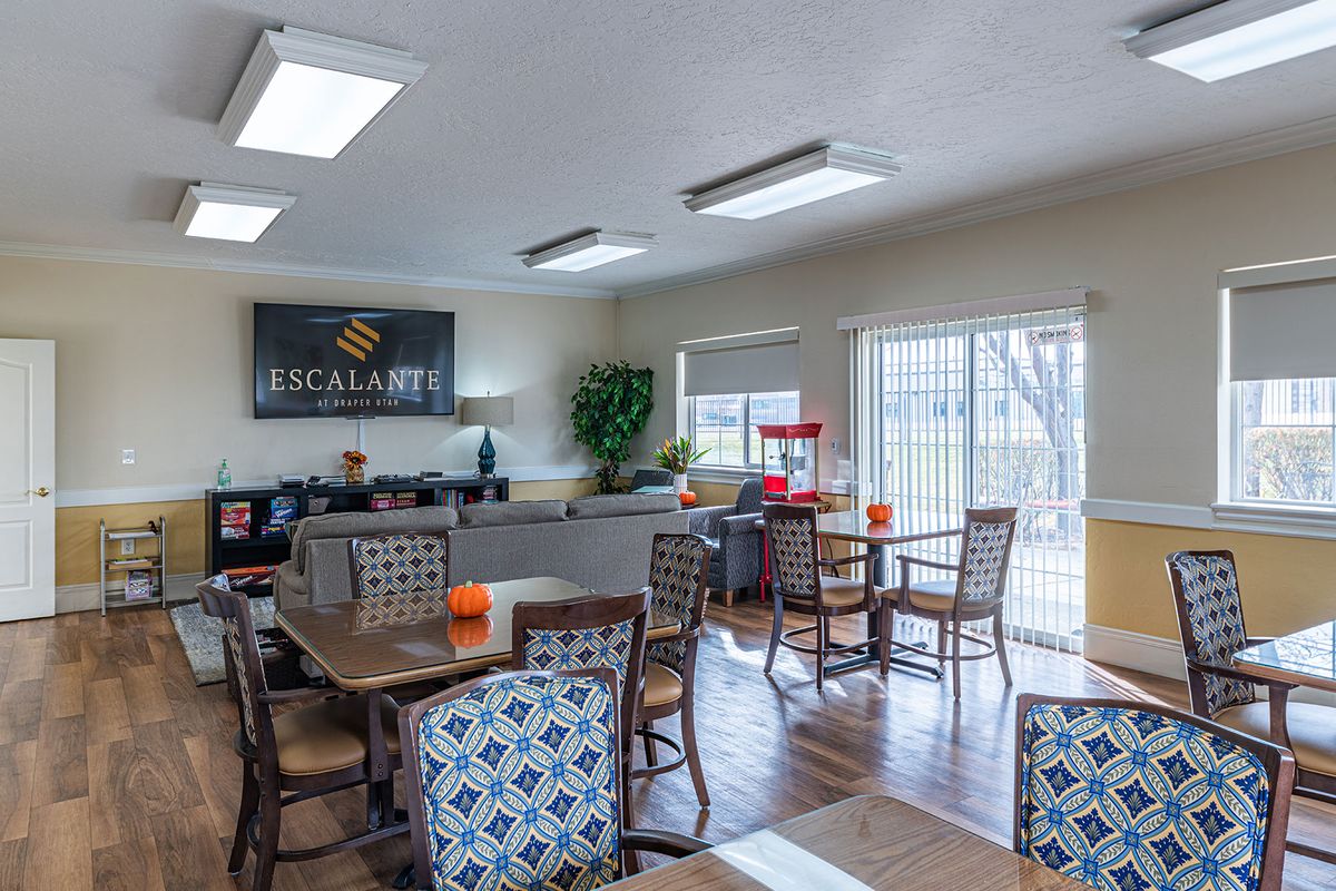 A well-lit community room with tables and chairs, featuring a popcorn machine and modern decor.