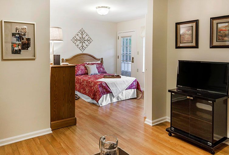 A cozy bedroom with a bed, television, and hardwood floors.