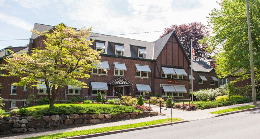 A charming exterior view of a hotel surrounded by greenery and a clear sky.