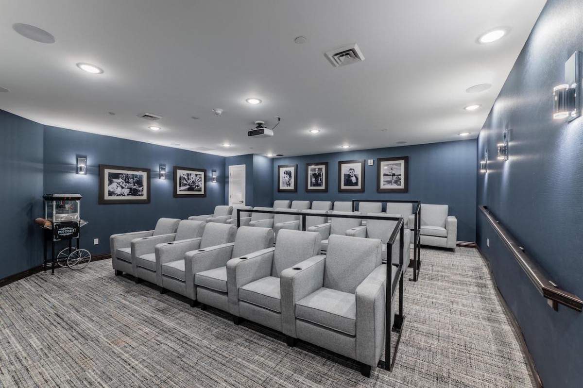 A modern home theater with comfortable seating and a projector, featuring blue walls and carpeted flooring.