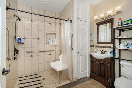 A spacious bathroom featuring a wheelchair accessible shower with a foldable seat and elegant vanity.