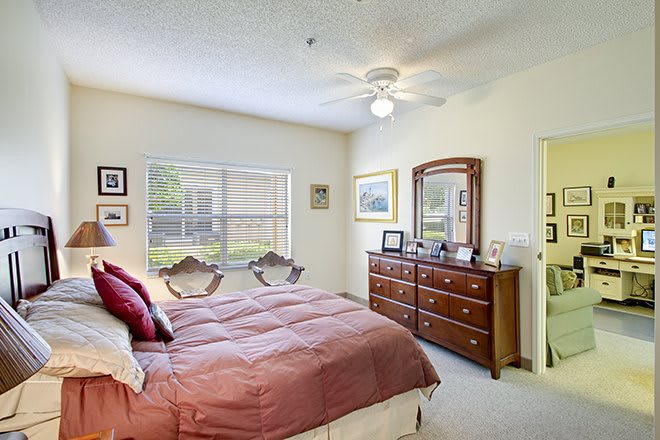 A cozy bedroom with a double bed, wooden dresser, and large window letting in natural light.