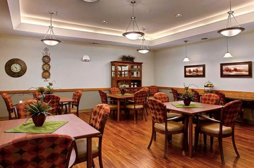 A cozy dining room with neatly arranged tables and chairs, complemented by warm lighting and decorative plants.