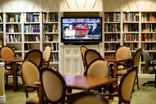 A cozy library setting featuring comfortable seating and a television displaying a program.