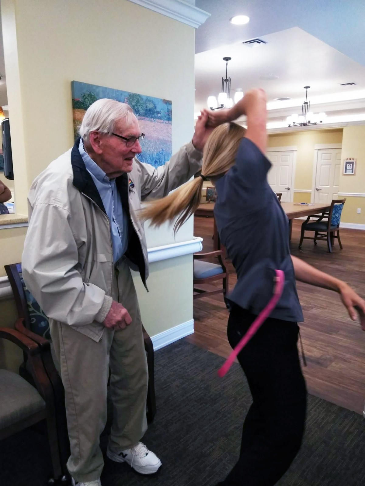 An elderly man joyfully dances with a woman indoors.