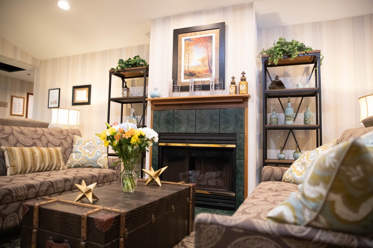 A cozy living room with a fireplace, bookshelves, and floral decor.