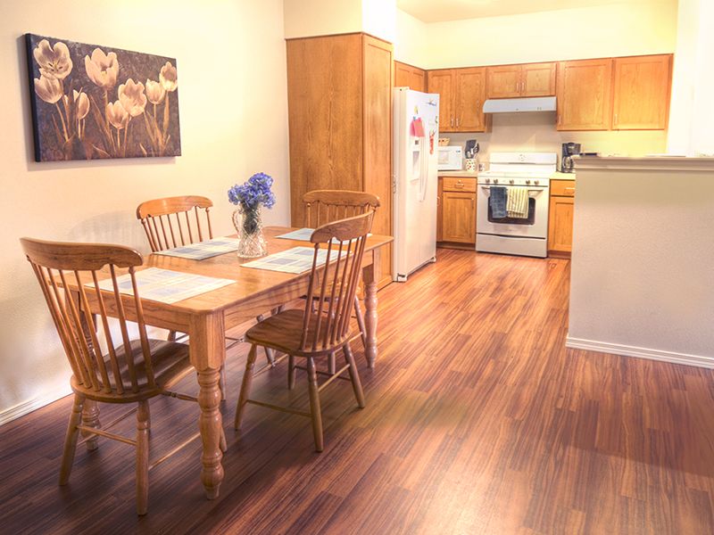 A cozy kitchen with a dining area featuring wooden floors and furniture, complete with modern appliances.