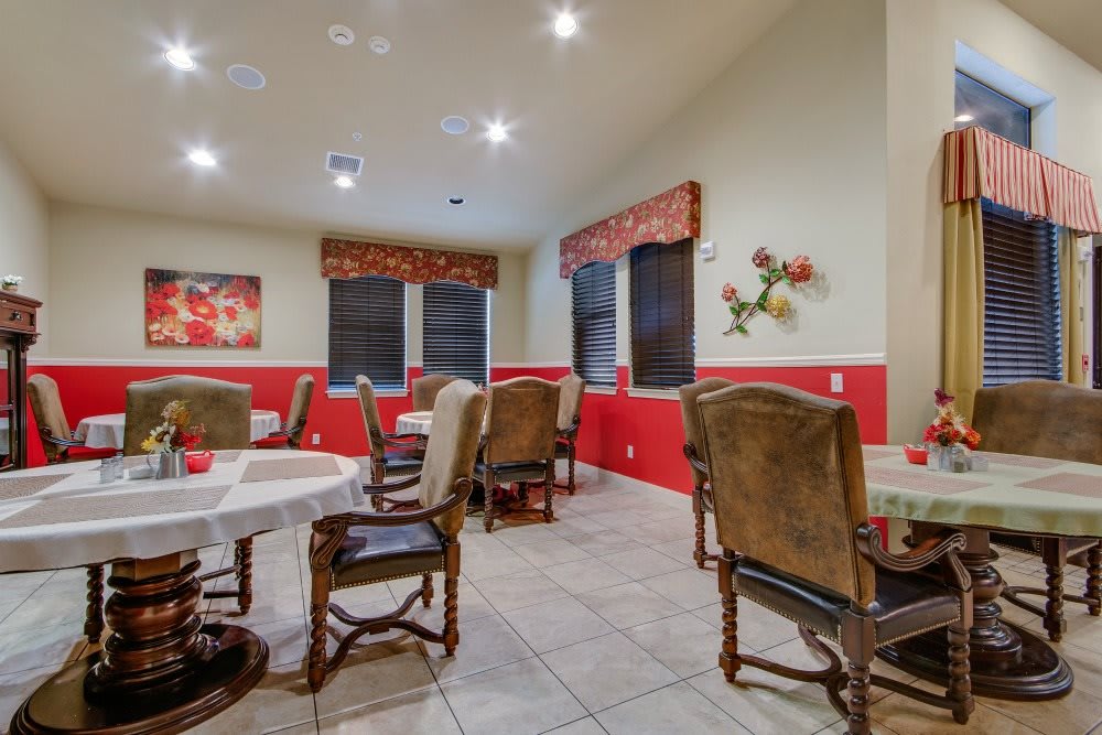 A cozy dining room with multiple tables and chairs, adorned with decorative paintings and soft lighting.