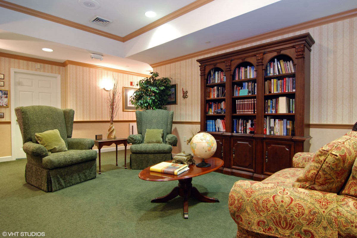 A cozy library with comfortable armchairs, a globe on the table, and bookshelves filled with books.