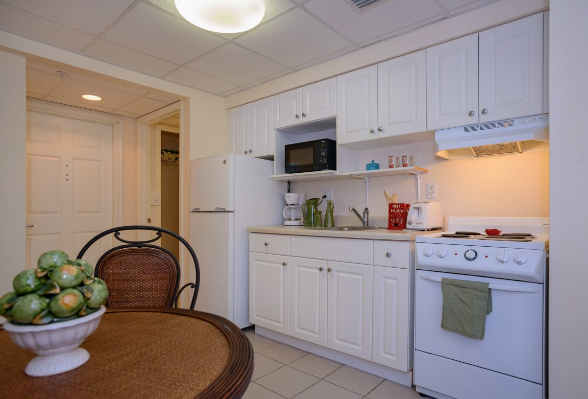 A small kitchen with white cabinets, a microwave, and a dining area.