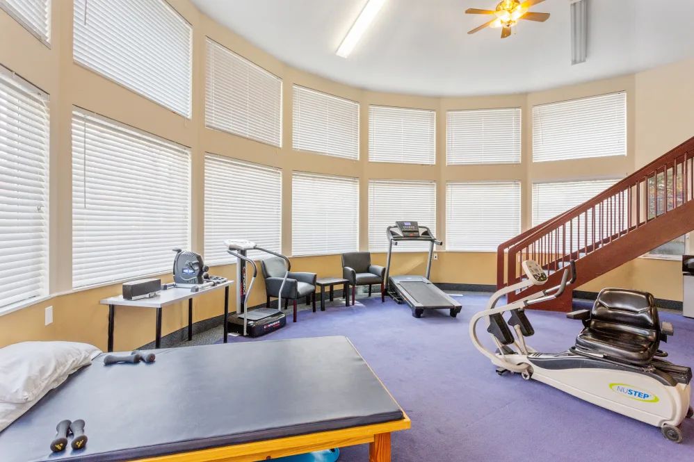 A home gym with various exercise equipment including a treadmill and weight machines.