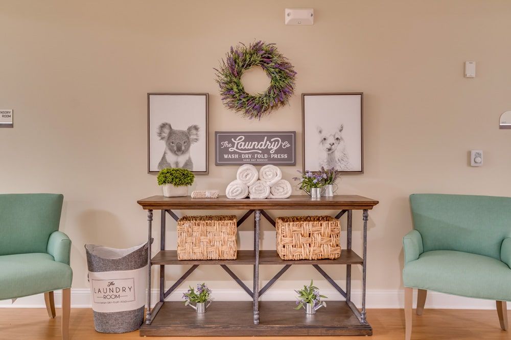 A neatly decorated entryway with a wreath and wall art above a table featuring baskets and small plants.