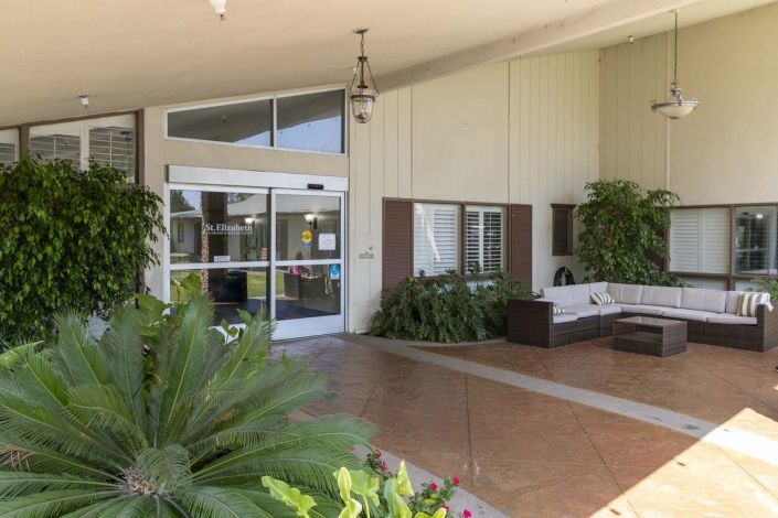 The entrance of a building with a seating area and plants.