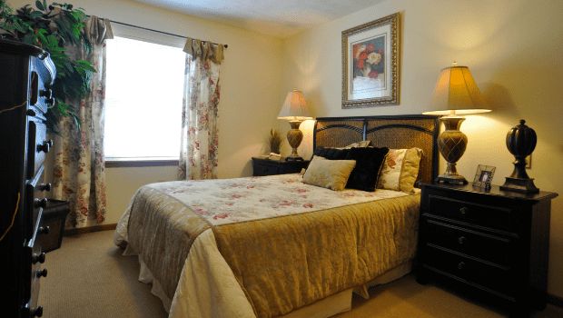 A cozy bedroom with a neatly made bed, bedside lamps, and elegant decor.