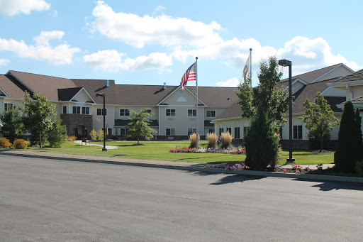 A hotel building with flags in front, surrounded by landscaped grounds under a clear blue sky.
