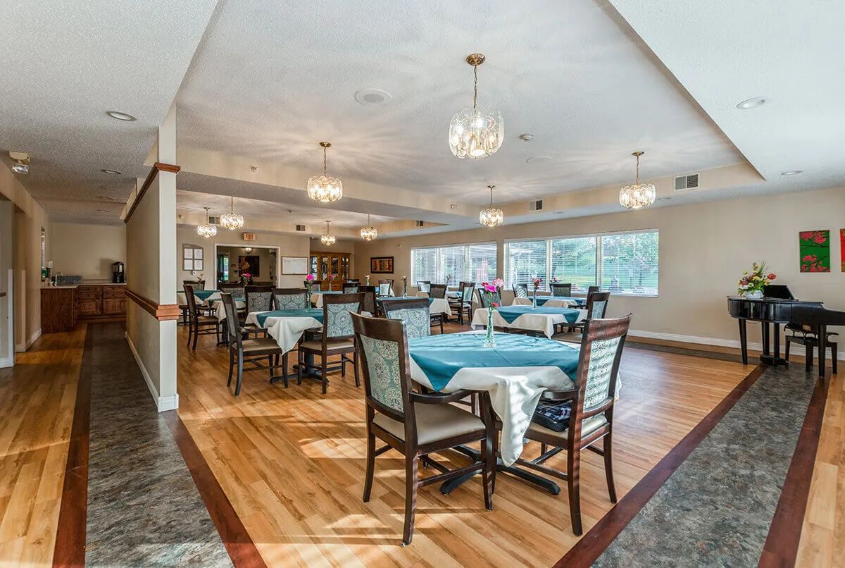 A spacious dining room with elegantly set tables and chandeliers.