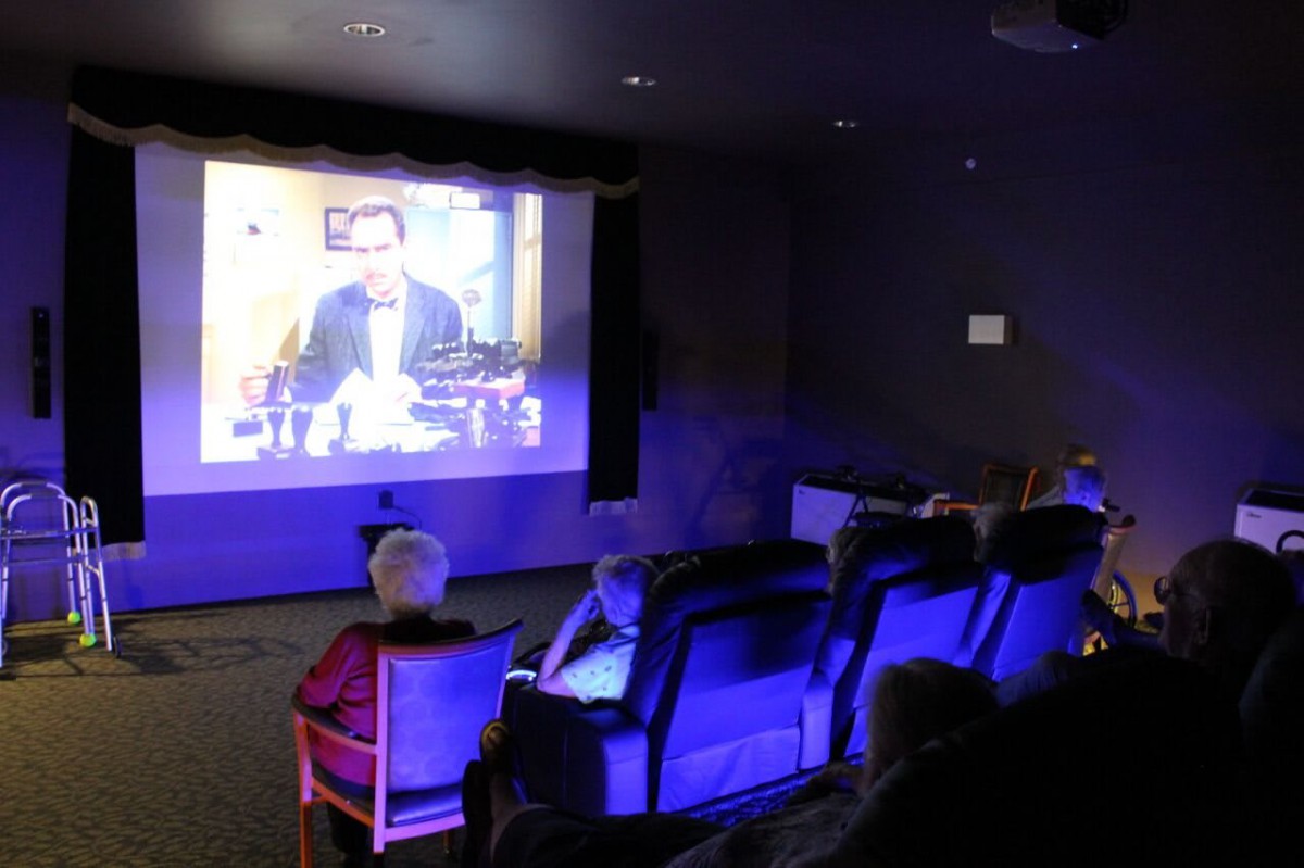 A group of people watching a movie in a cozy home theater setting.