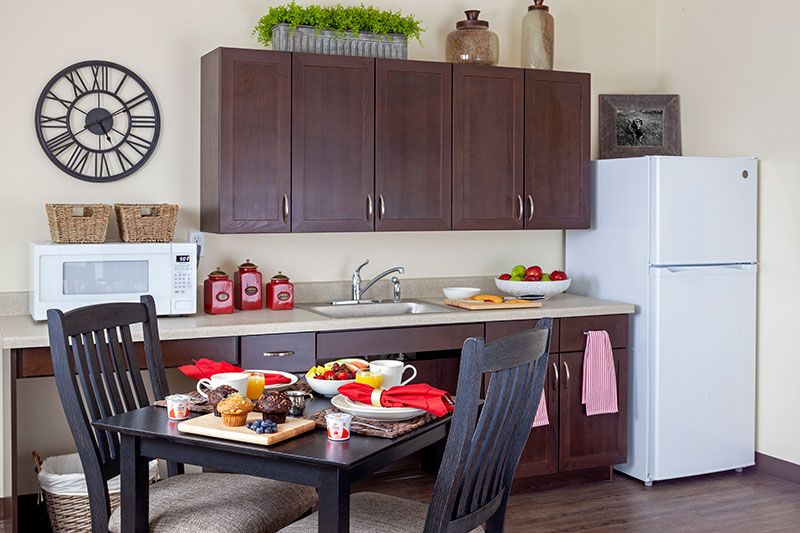A cozy kitchen with a dining table set for breakfast, featuring dark wooden cabinets and modern appliances.