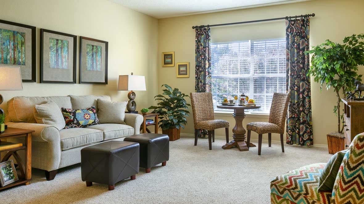 A cozy living room with a sofa, table and chairs, large window, and tasteful decorations.